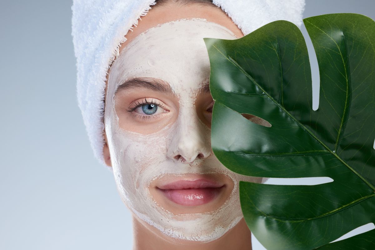 woman wears sheet mask with leaf in front of face
